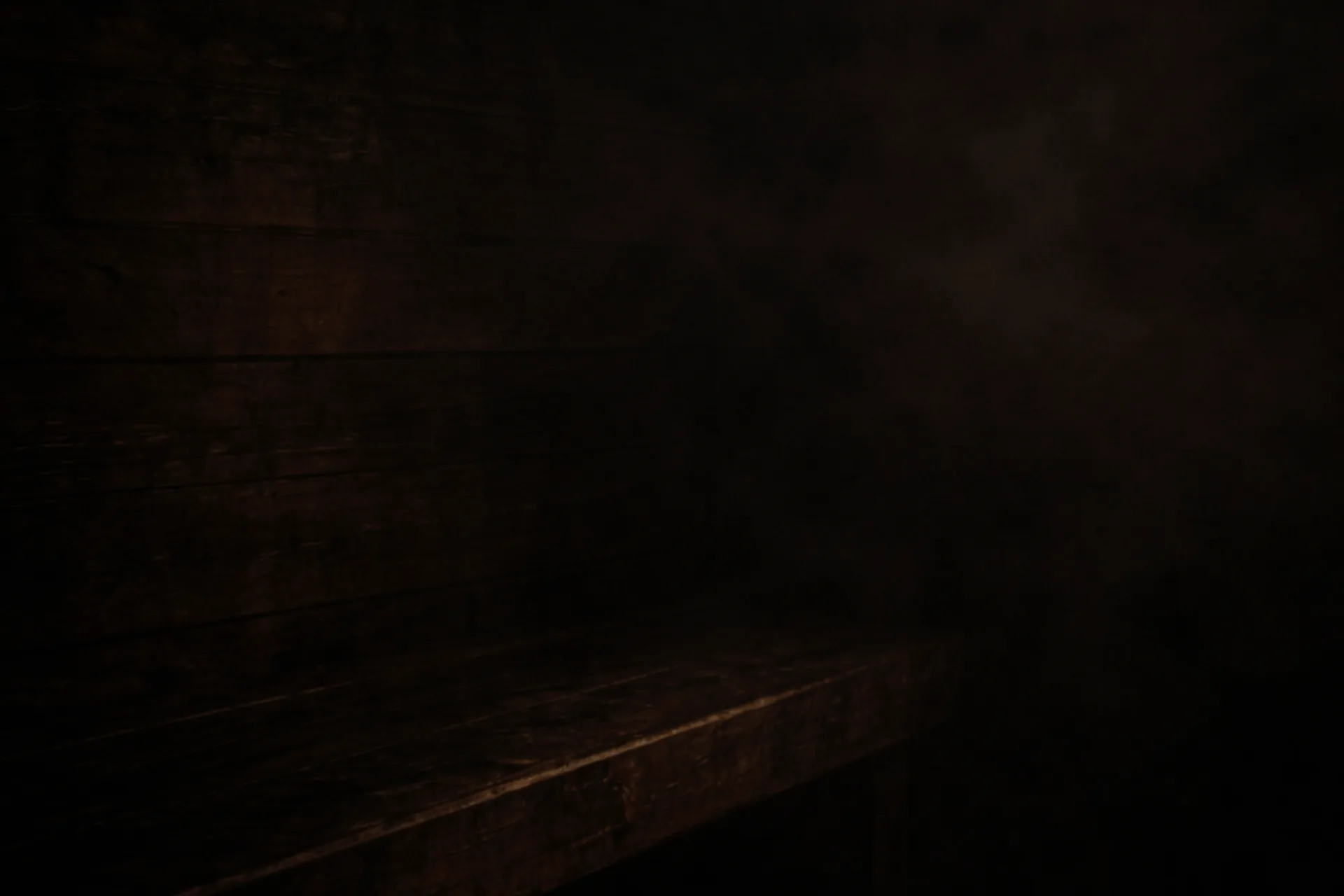 Interior of a traditional Finnish sauna, dark aged timber bench, subtle steam haze